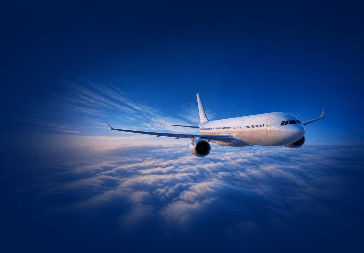 Unbranded passenger aircraft flying above clouds in a royal-blue sky